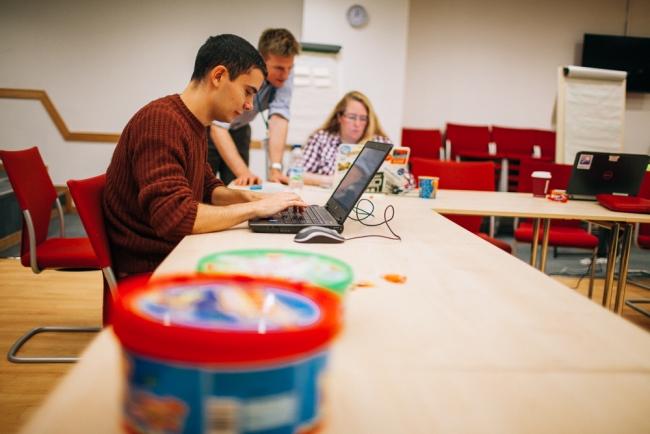 People working on laptops with jar of sweets in foreground