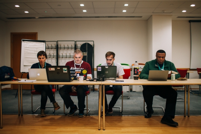 four people in a row working on laptops