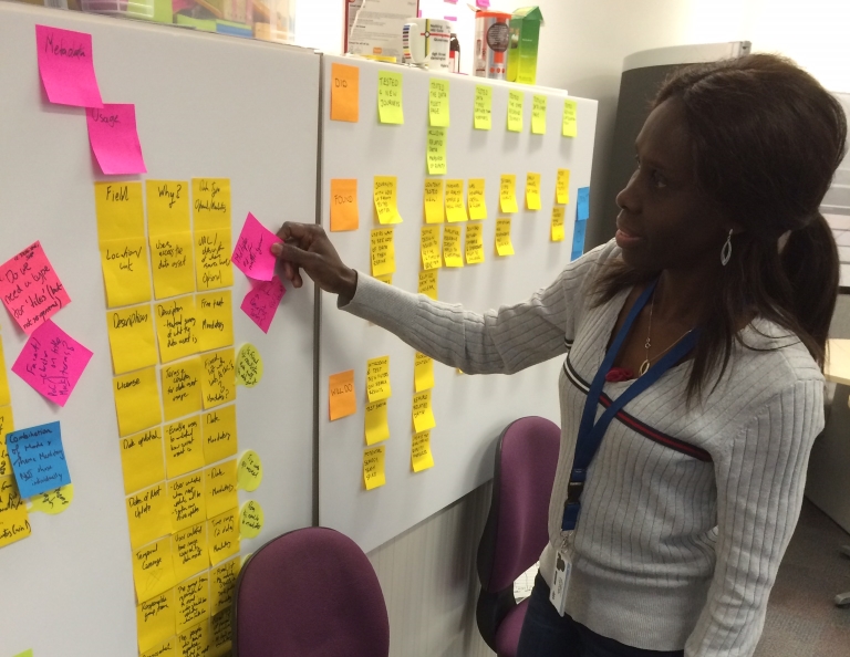 woman putting Post-it note on a kanban board