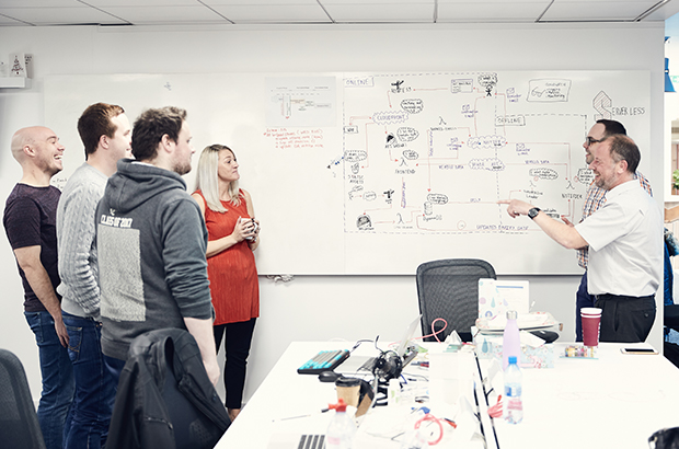 A group of civil servants stood in front of a road map having a jovial discussion