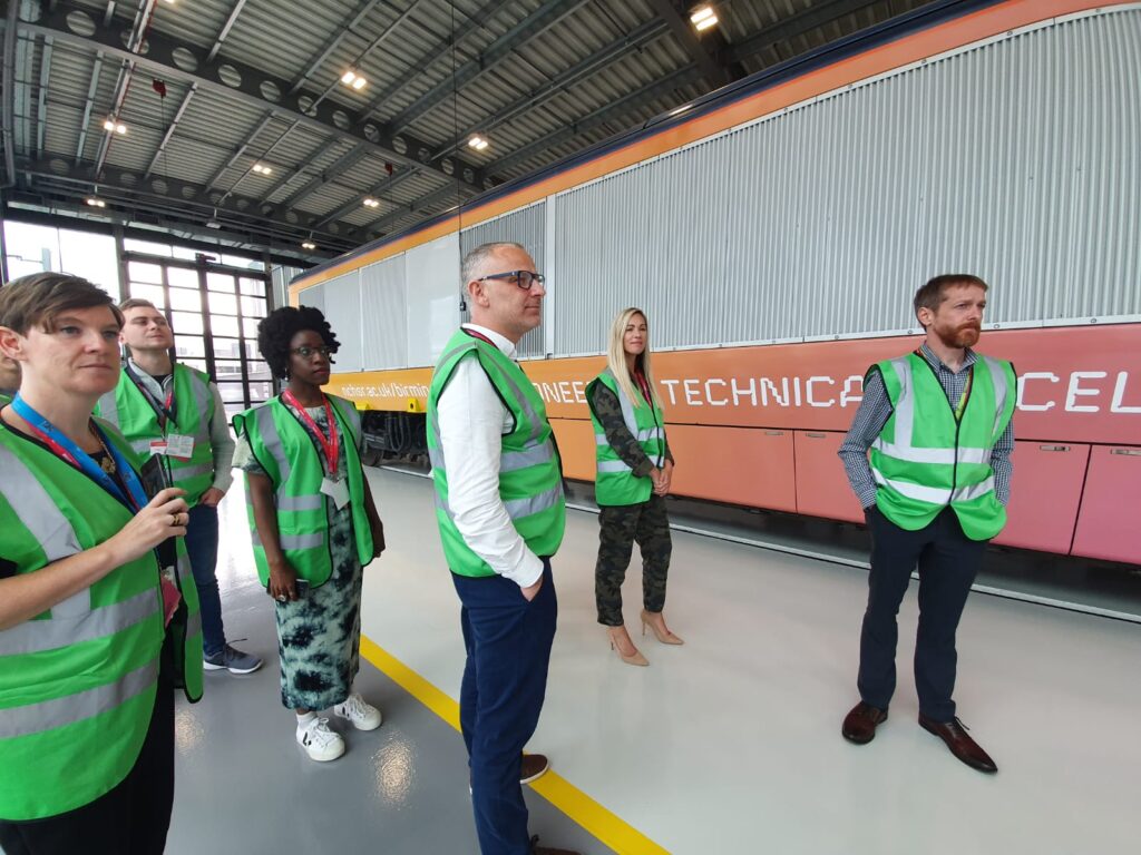 An image of 6 civil servants in high visibility vests learning about high speed rail in front of a train