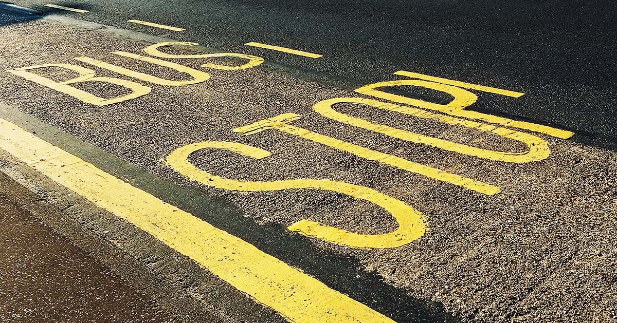 Bus stop painted lettering on tarmac road